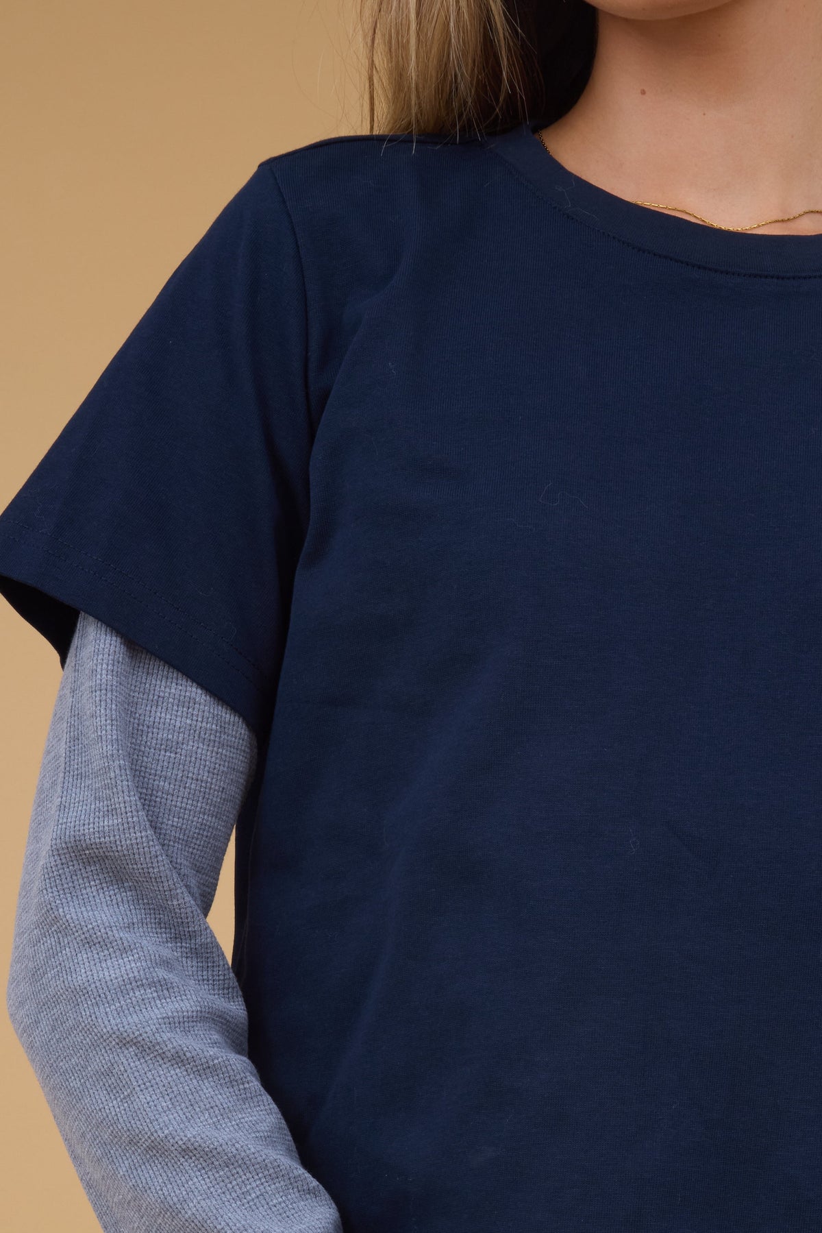 Close up view of a woman wearing a navy short sleeve tee with long waffle eave sleeves.