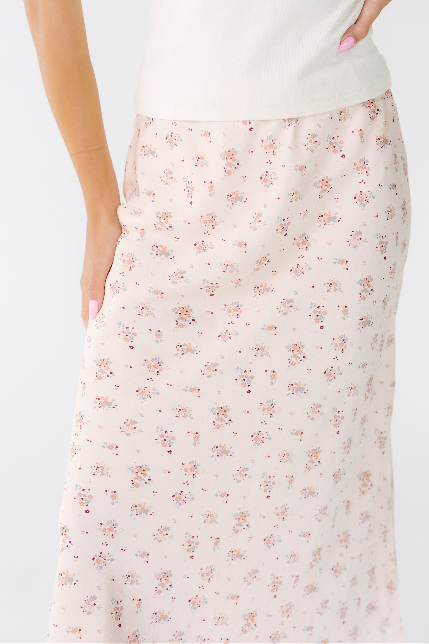 Close view of a woman wearing an A-line pink floral midi skirt.