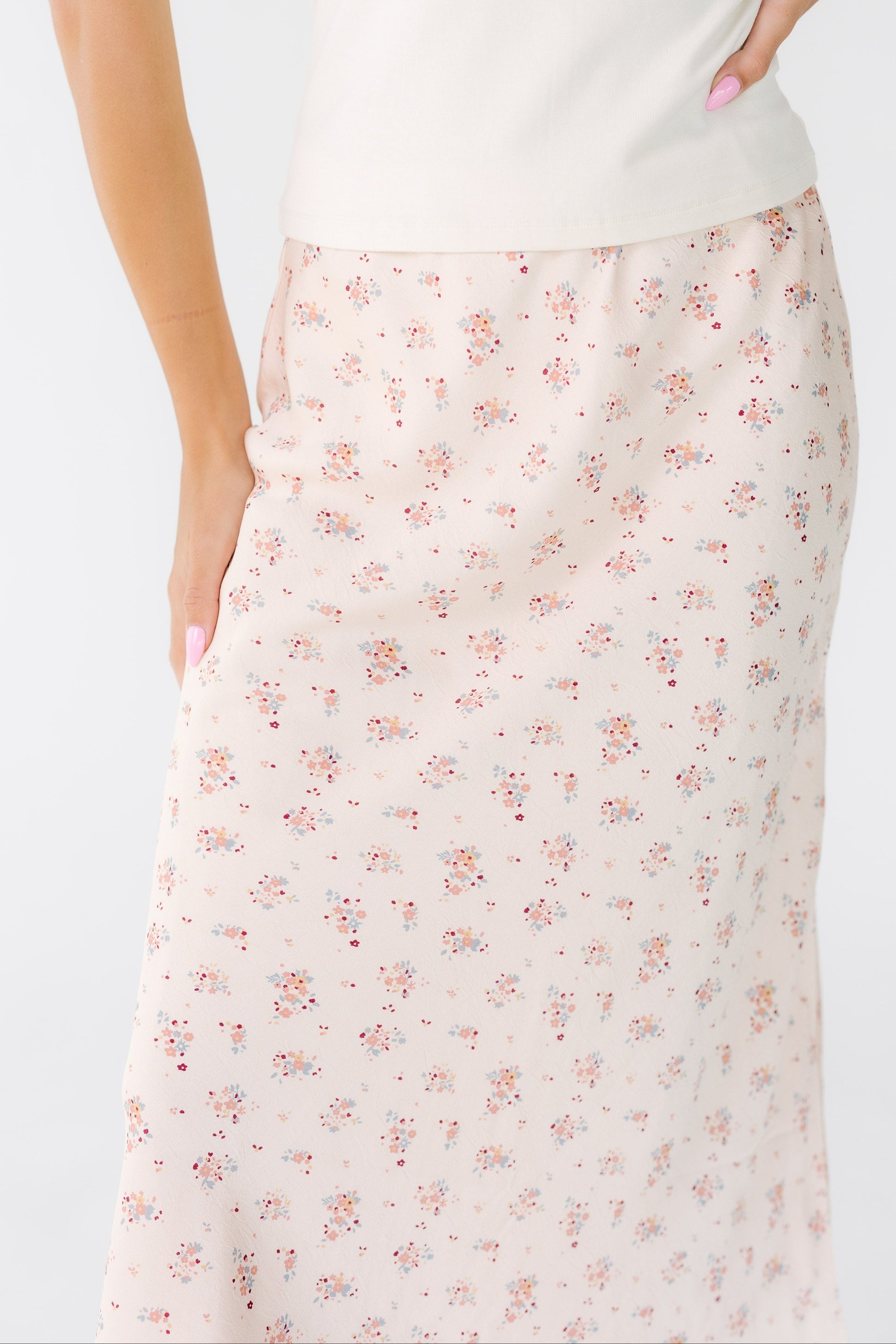 Close view of a woman wearing an A-line pink floral midi skirt.