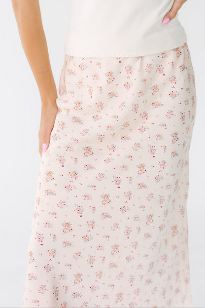 Close view of a woman wearing an A-line pink floral midi skirt.