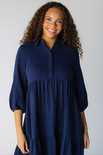 Close view of a teen girl wearing a navy dress with a V-neckline, pointed collar and three quarter length sleeves