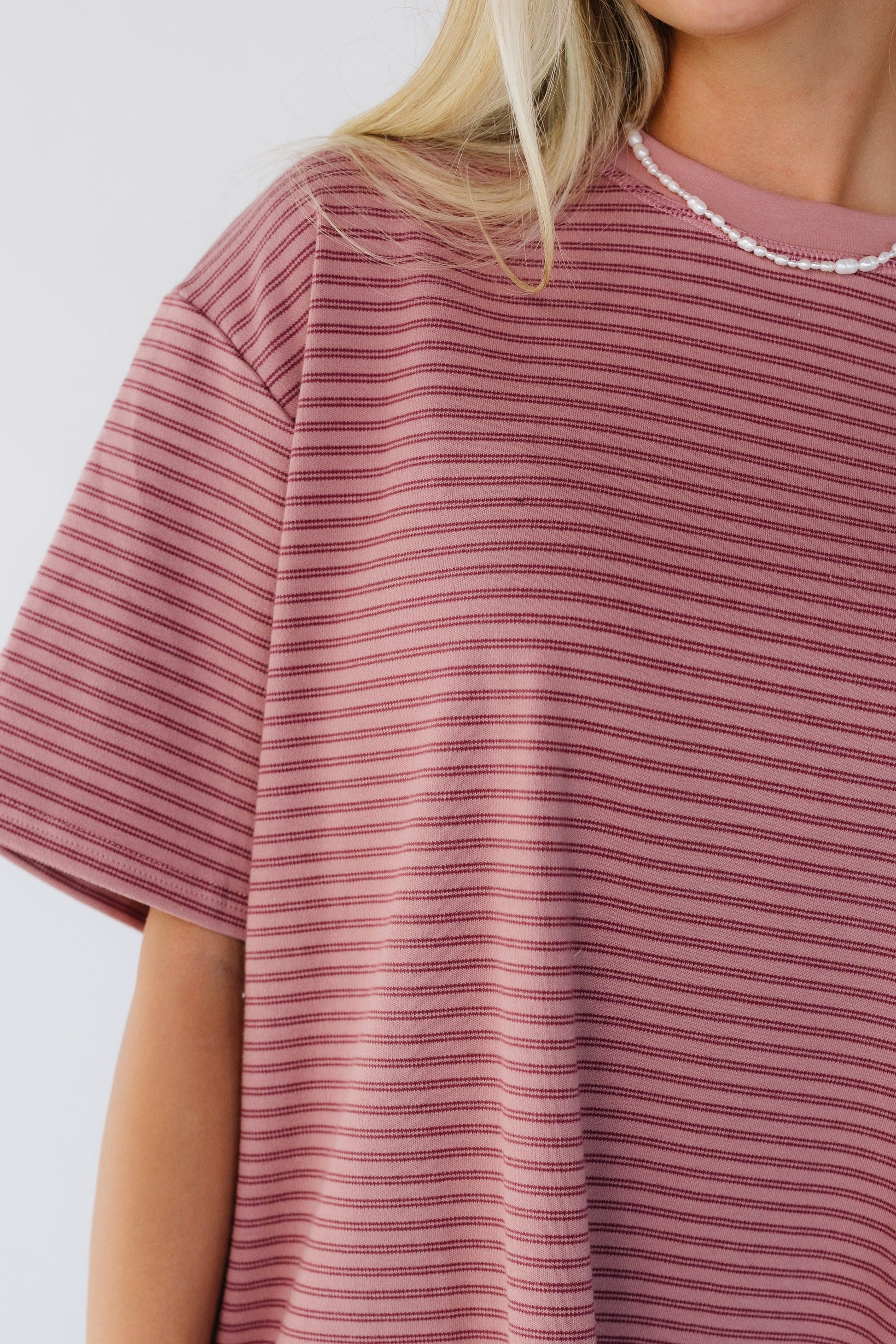 Close view of a woman wearing a pink stripe oversized tee with short sleeves.