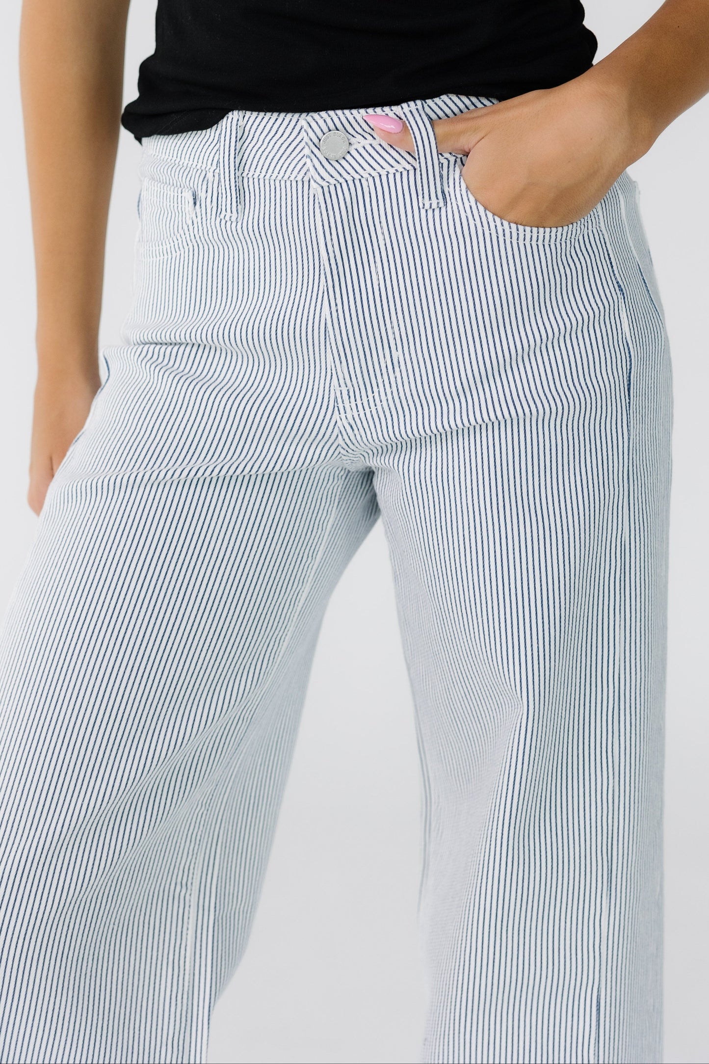 Close view of a woman wearing white wide leg jeans with thin navy stripes.