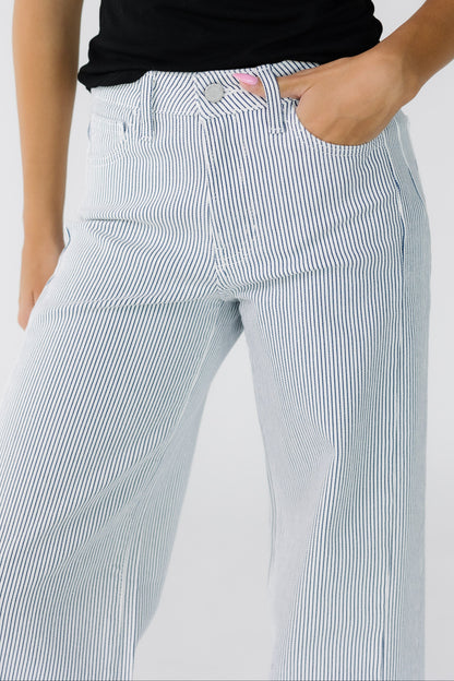 Close view of a woman wearing white wide leg jeans with thin navy stripes.
