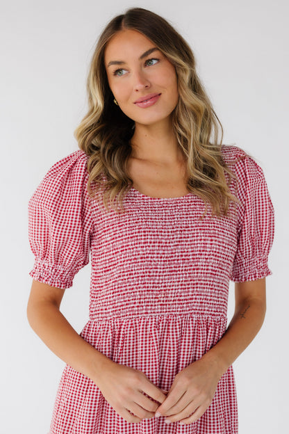 Close bodice view of a woman wearing a red & white gingham dress with a scoop neckline, short puff sleeves and a smocked bodice - front & back.