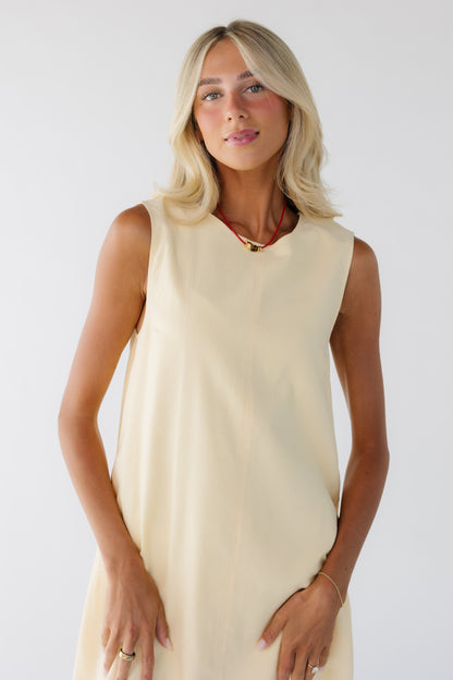 Close view of a woman wearing a yellow sleeveless dress with a round neckline.