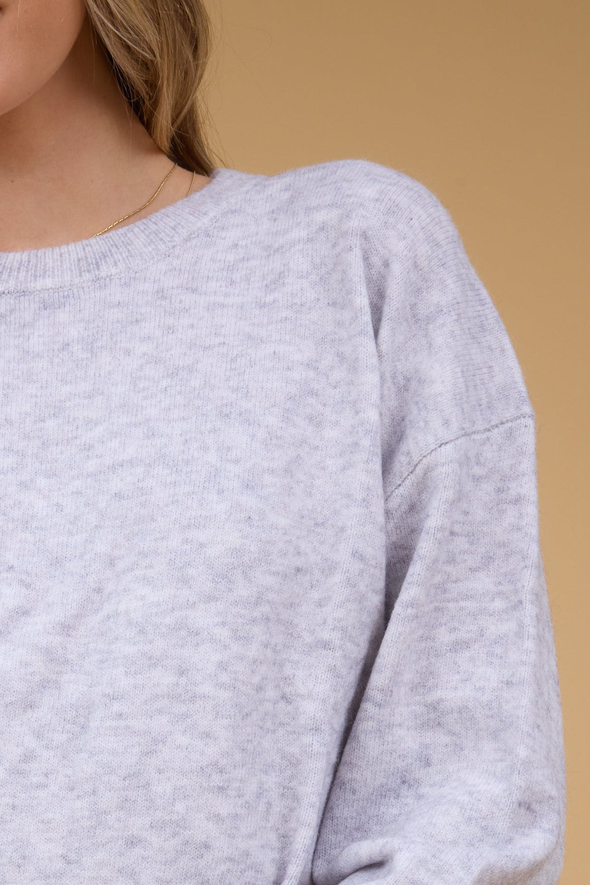 Close up view of a woman wearing a slightly loose fitting sweater with drop shoulders.