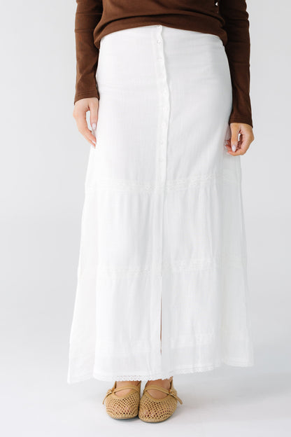Woman wearing a modest  A-line button down midi skirt with a center front slit with 3 white lace stripes.
