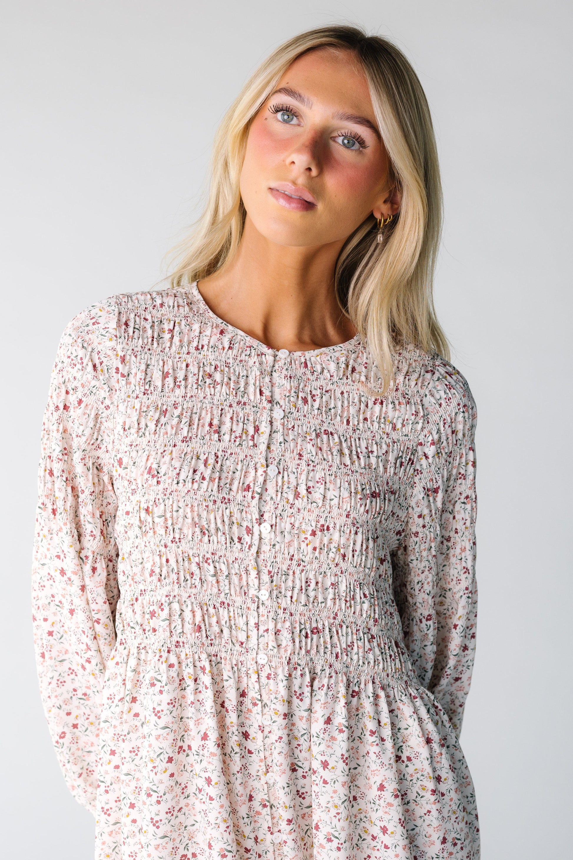 Close view of a woman wearing a cream floral print dress with a smocked bodice