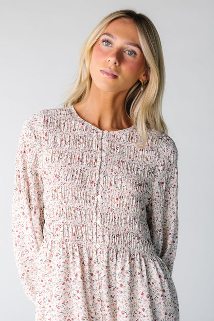 Close view of a woman wearing a cream floral print dress with a smocked bodice