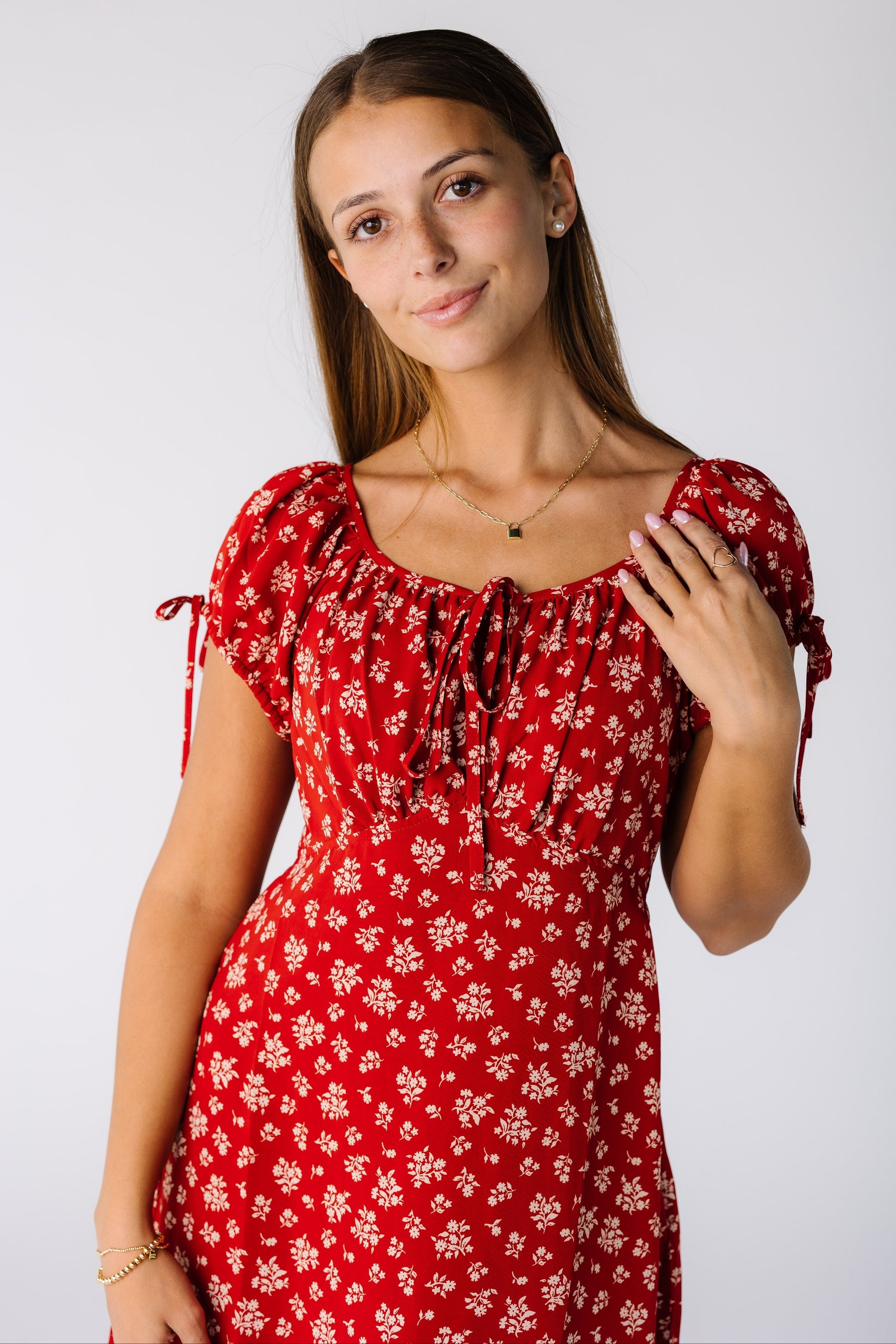 Cloe view of a woman wearing a red and white print dress with a scoop neckline, short sleeve and empire waist
