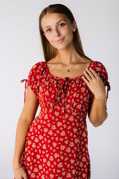 Cloe view of a woman wearing a red and white print dress with a scoop neckline, short sleeve and empire waist