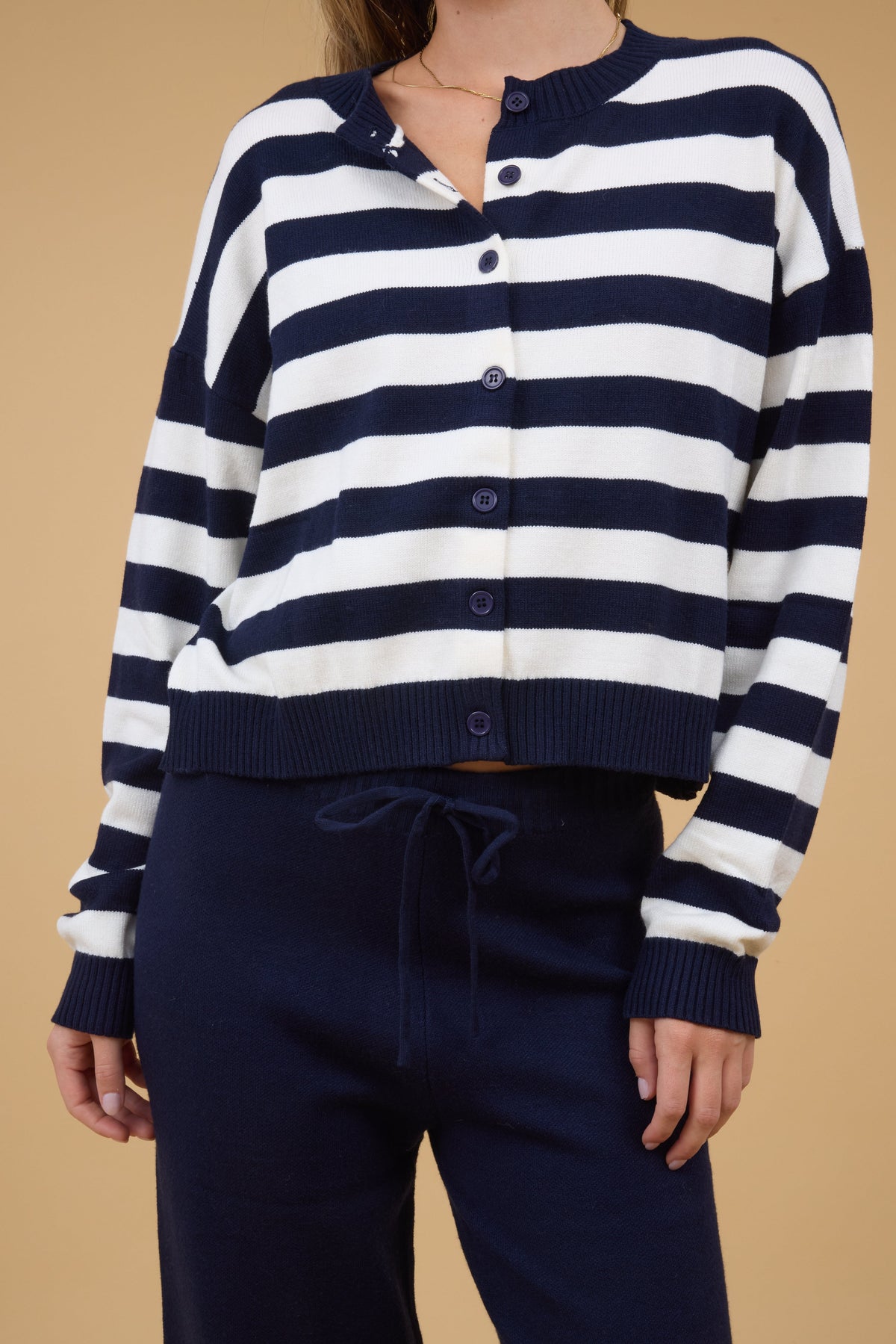 Close view of a woman wearing a navy & white stripe cardigan with bnavy sweater pants.