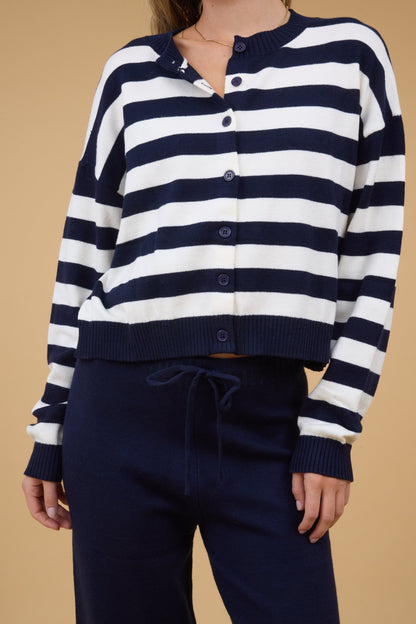 Close view of a woman wearing a navy & white stripe cardigan with bnavy sweater pants.