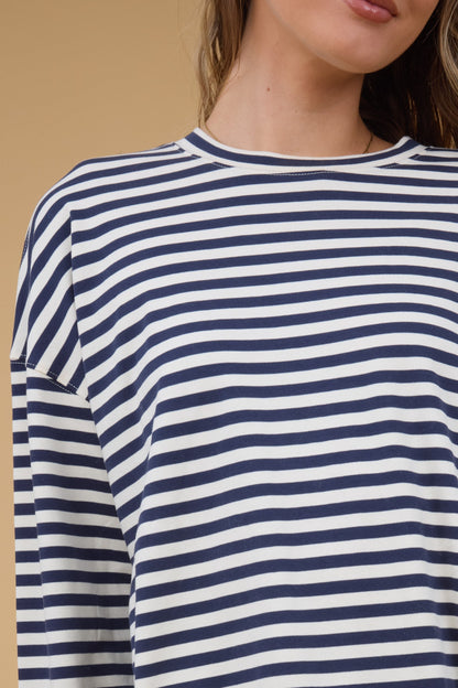 Close view of a woman wearing a navy & white stripes with a round neckine and long sleeves.