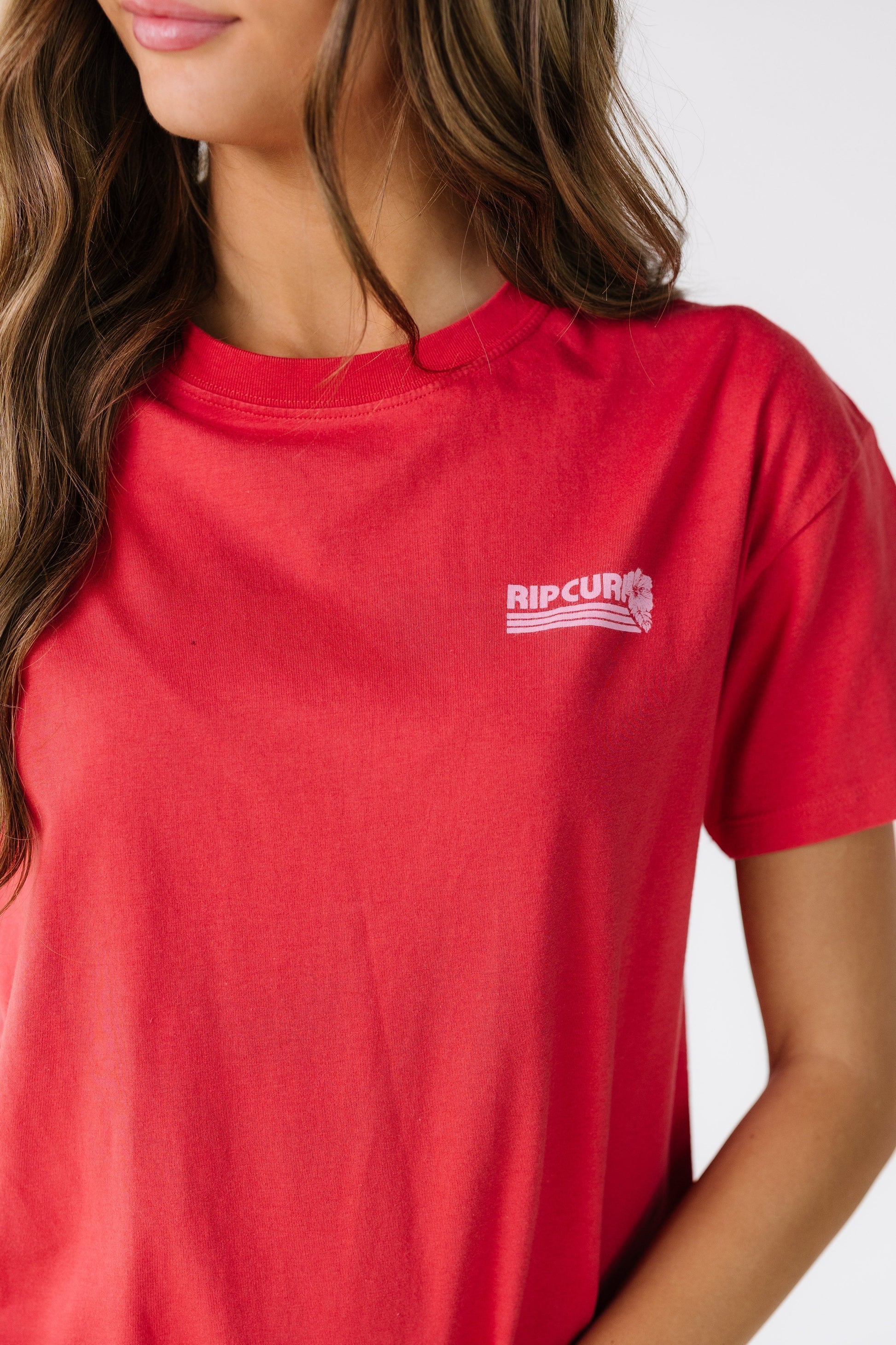 Close view of a young woman wearing a red graphic tee with a small front graphic.