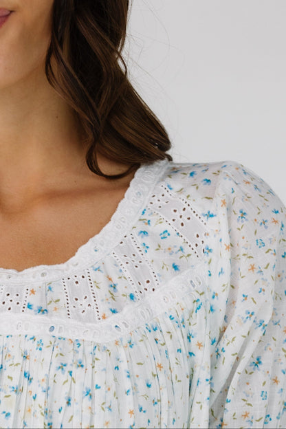 Close view of a woman wearing a blue & white floral print and eyelet lace.