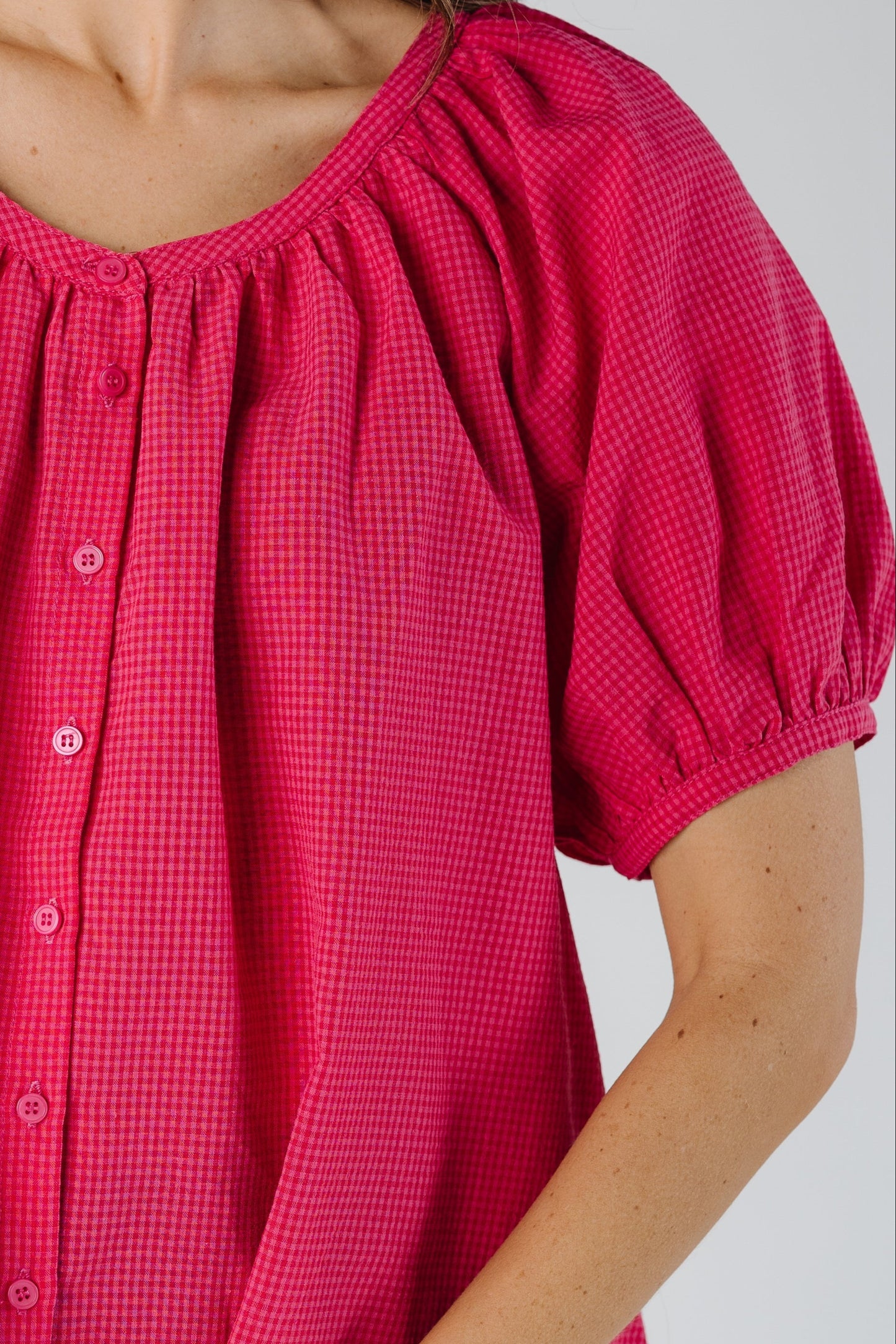 Close view of bright pink gingham button down top