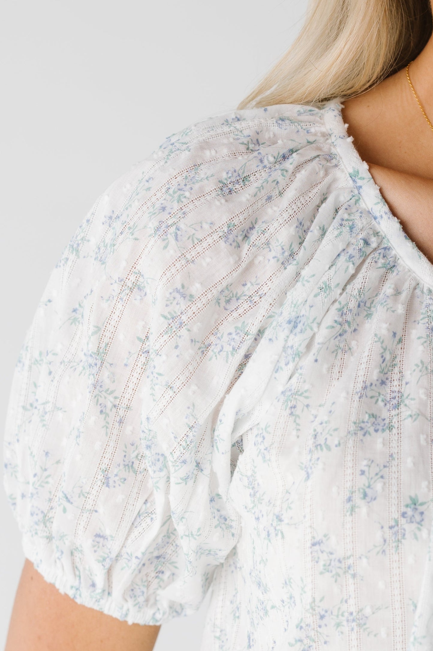 Very close view of white woven top with blue floral print