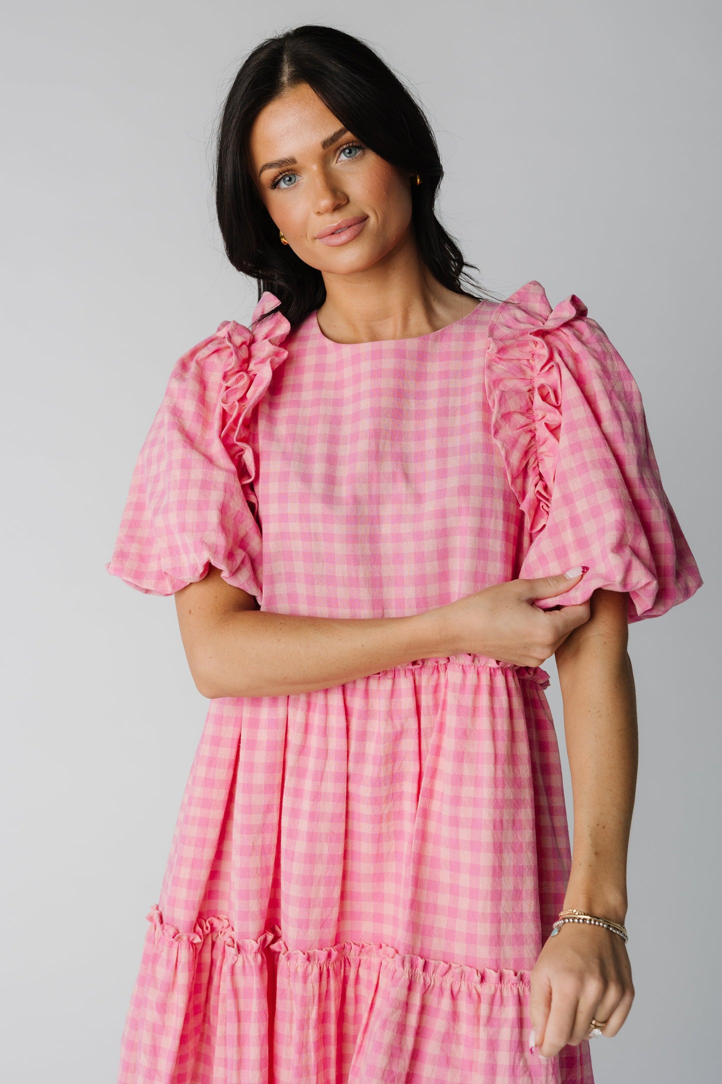 Close view of pink gingham dress with ruffles over shoulder and wide bottom ruffle