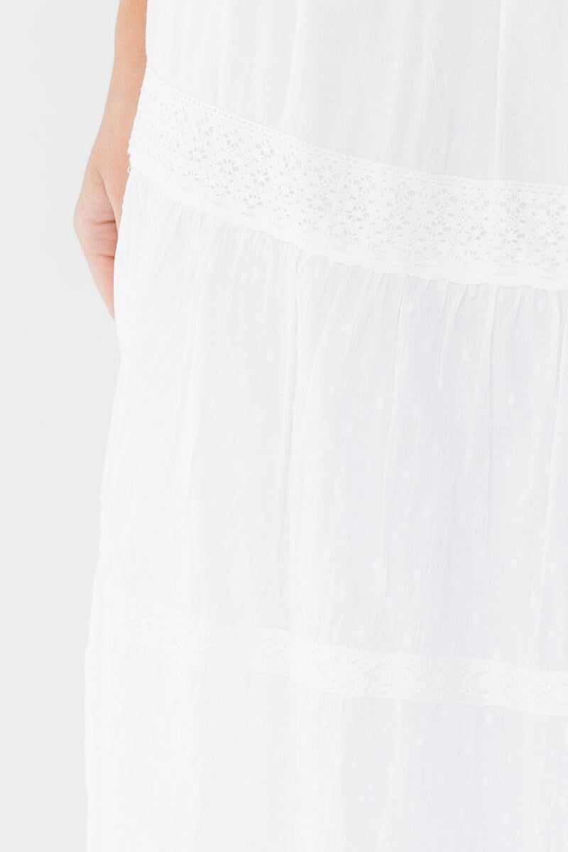Close view of a woman wearing a white tiered and lace trimmed midi skirt.