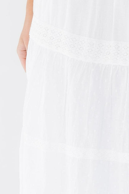 Close view of a woman wearing a white tiered and lace trimmed midi skirt.