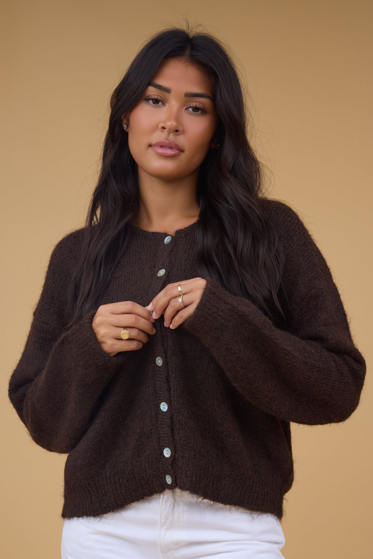 Young woman wearing a modest brown rib knit cardigan with contrasting buttons and long sleeves.