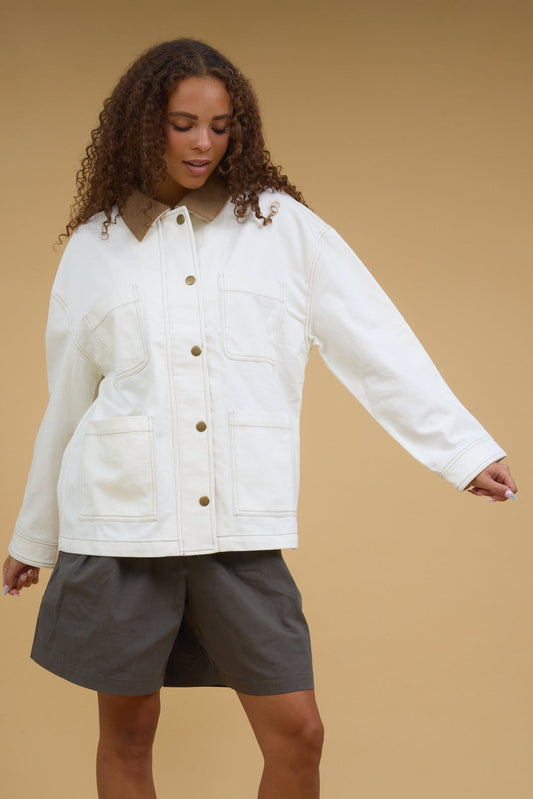 Young woman wearing a modest ecru jacket with front patch pockets, corduroy collar and a zipper &  snap closure.