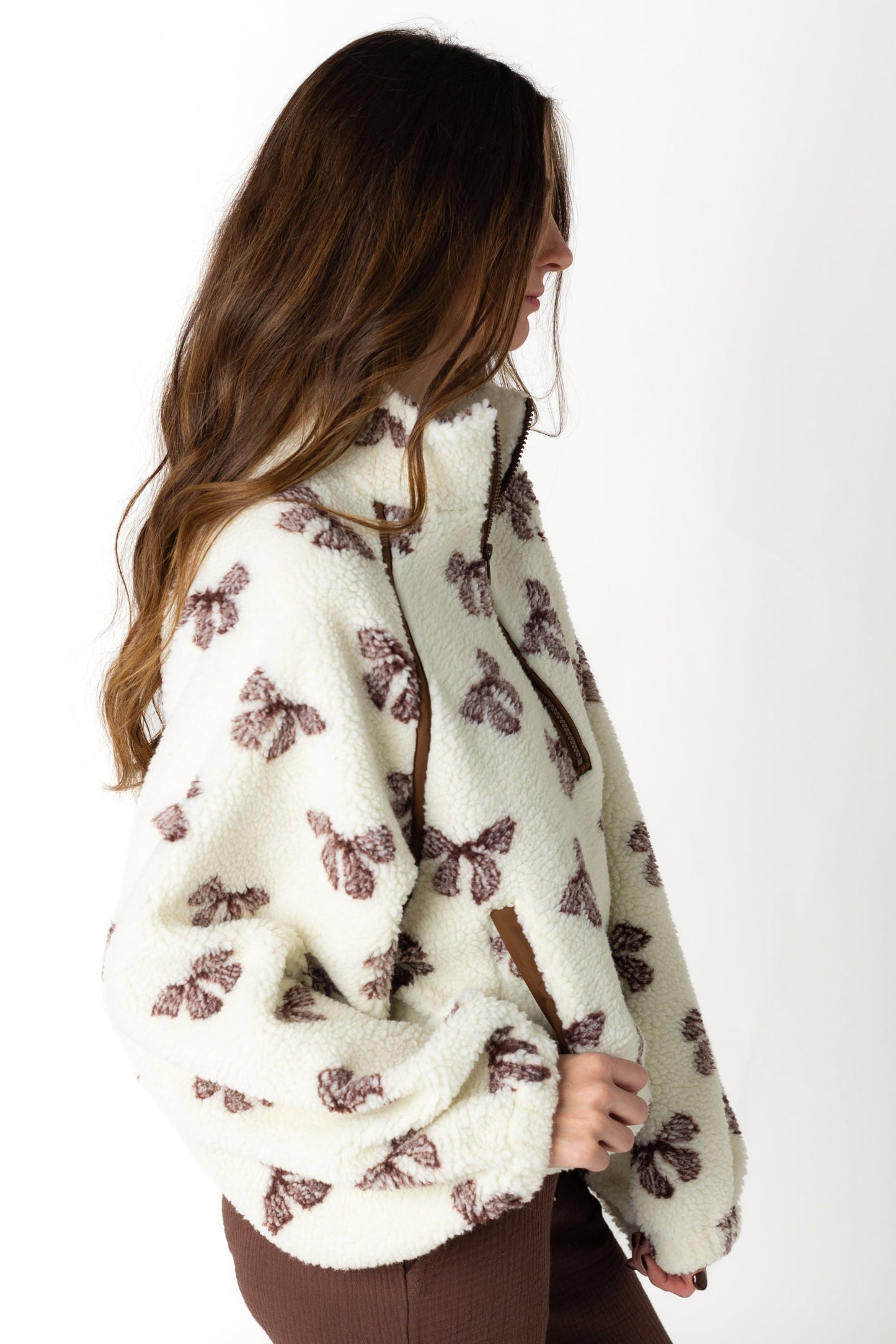 Side view of cream sherpa jacket with bow patterned print