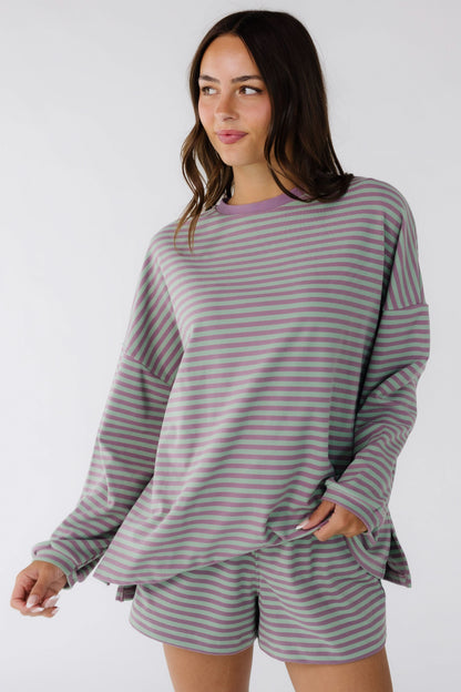 Young woman wearing an oversized purple and green stripe short set with a crew neckline and drop shoulders.
