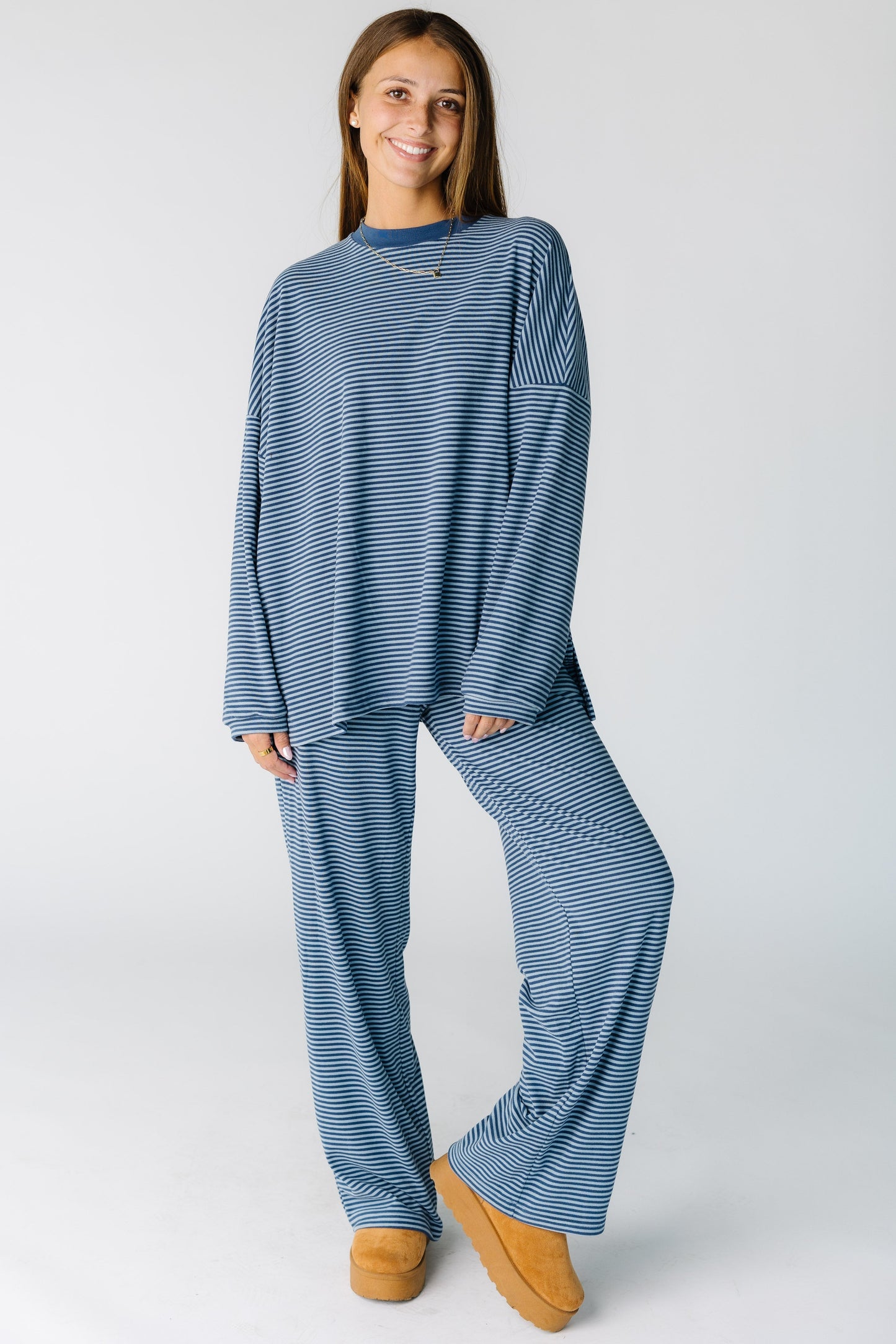 Woman wearing a  modest blue and white stripe lounge set with long sleeves and wide full length jeans