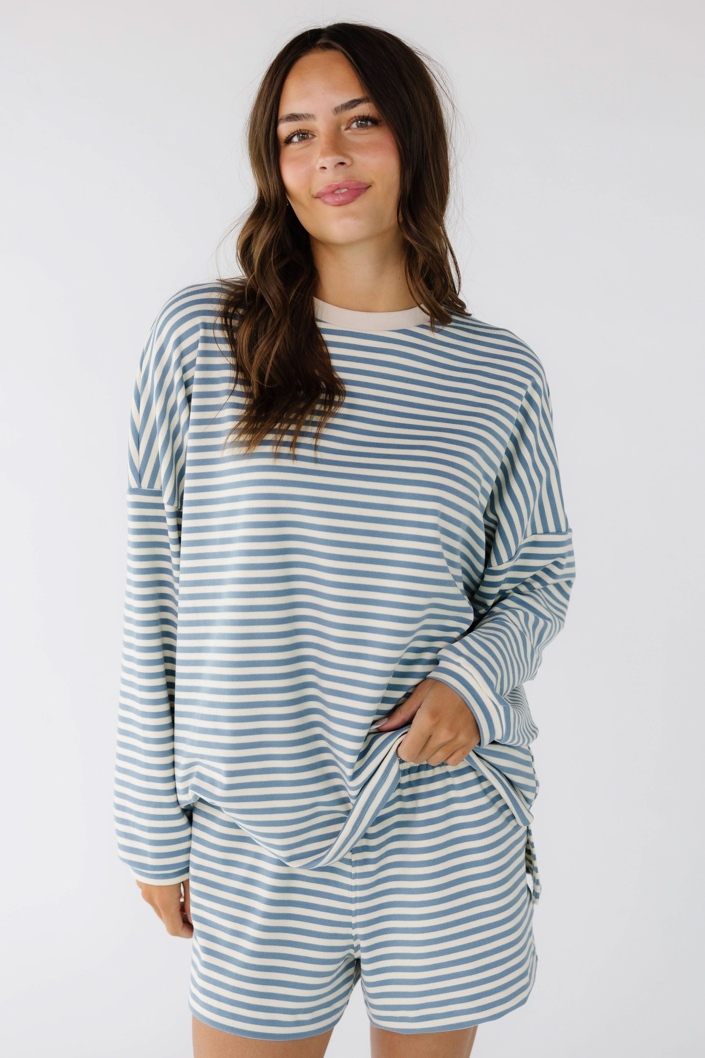 Young woman wearing a cream & blue oversized short set with an elastic waistband, drop shoulders and long sleeves.