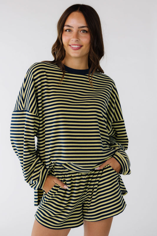 Young woman wearing a loose navy and yellow stripe shorts set with long sleeves, an elastic waistband and pockets.