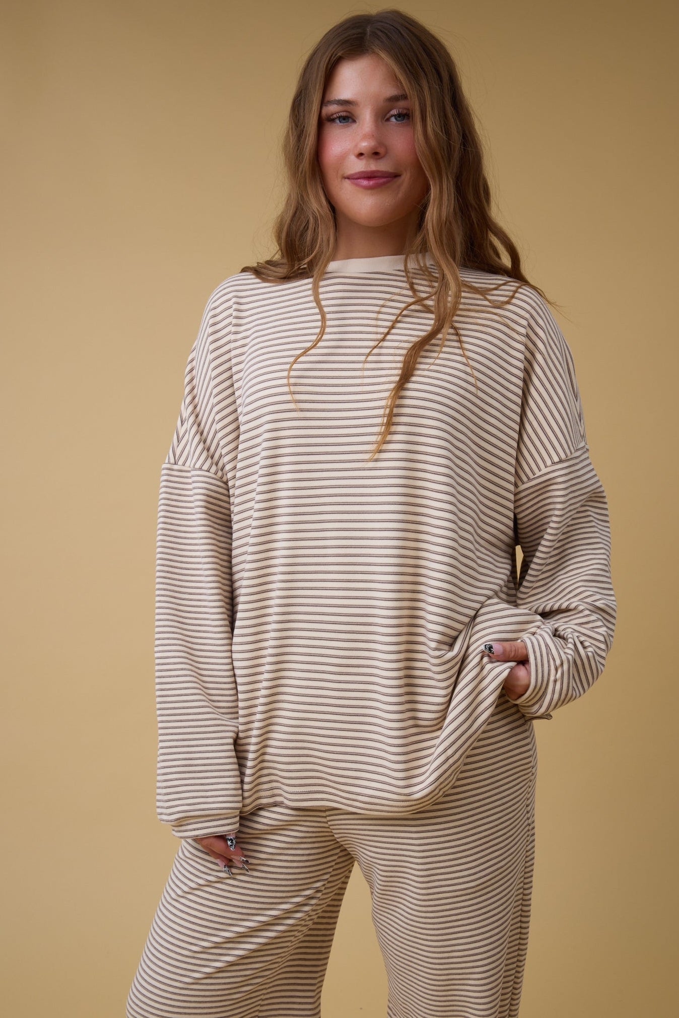 Young woman wearing a modest stripe lounge set in tan stripe.