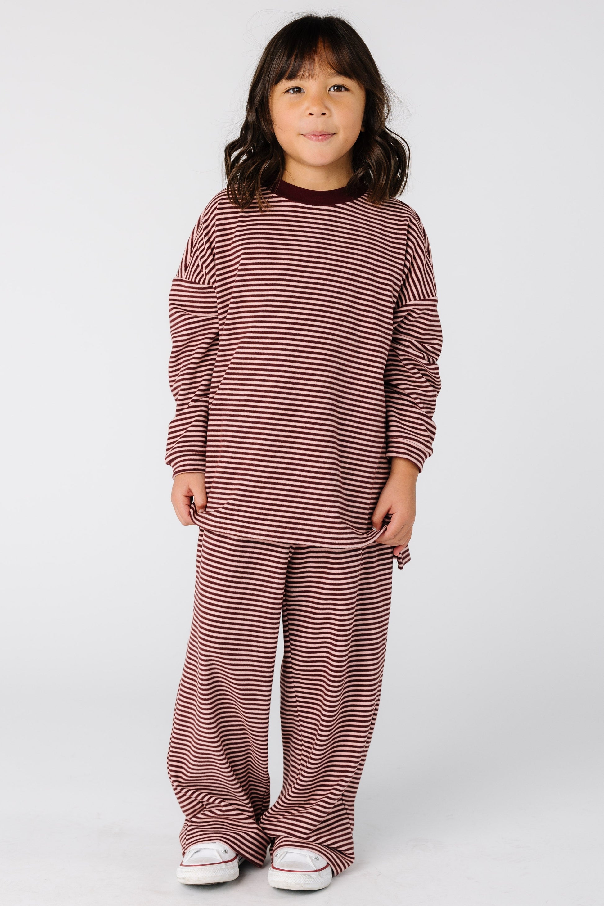 Girl wearing a modest stripe lounge set in burgundy with with long sleeves and full length pants