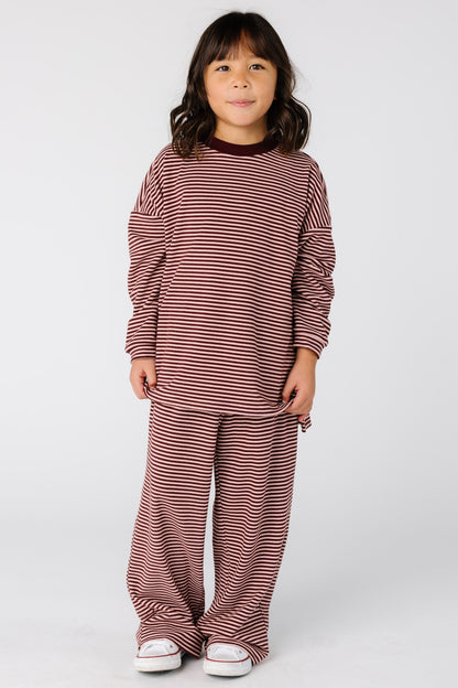 Girl wearing a modest stripe lounge set in burgundy with with long sleeves and full length pants