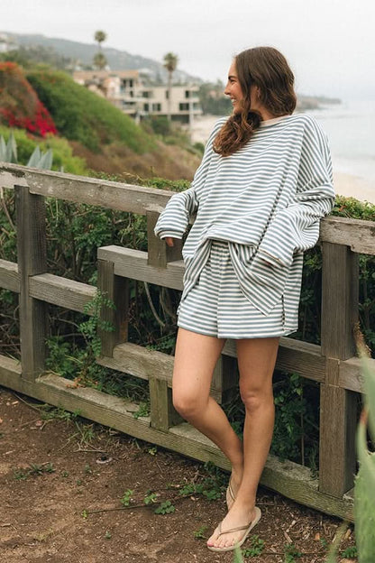 Woman wearing a blue and cream stripe shorts set standing in a garden.