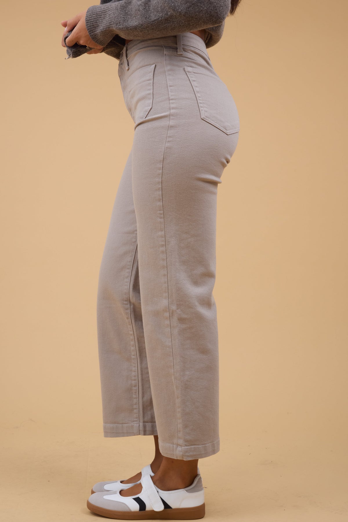 Side view of a woman wearing tan straight leg jeans.