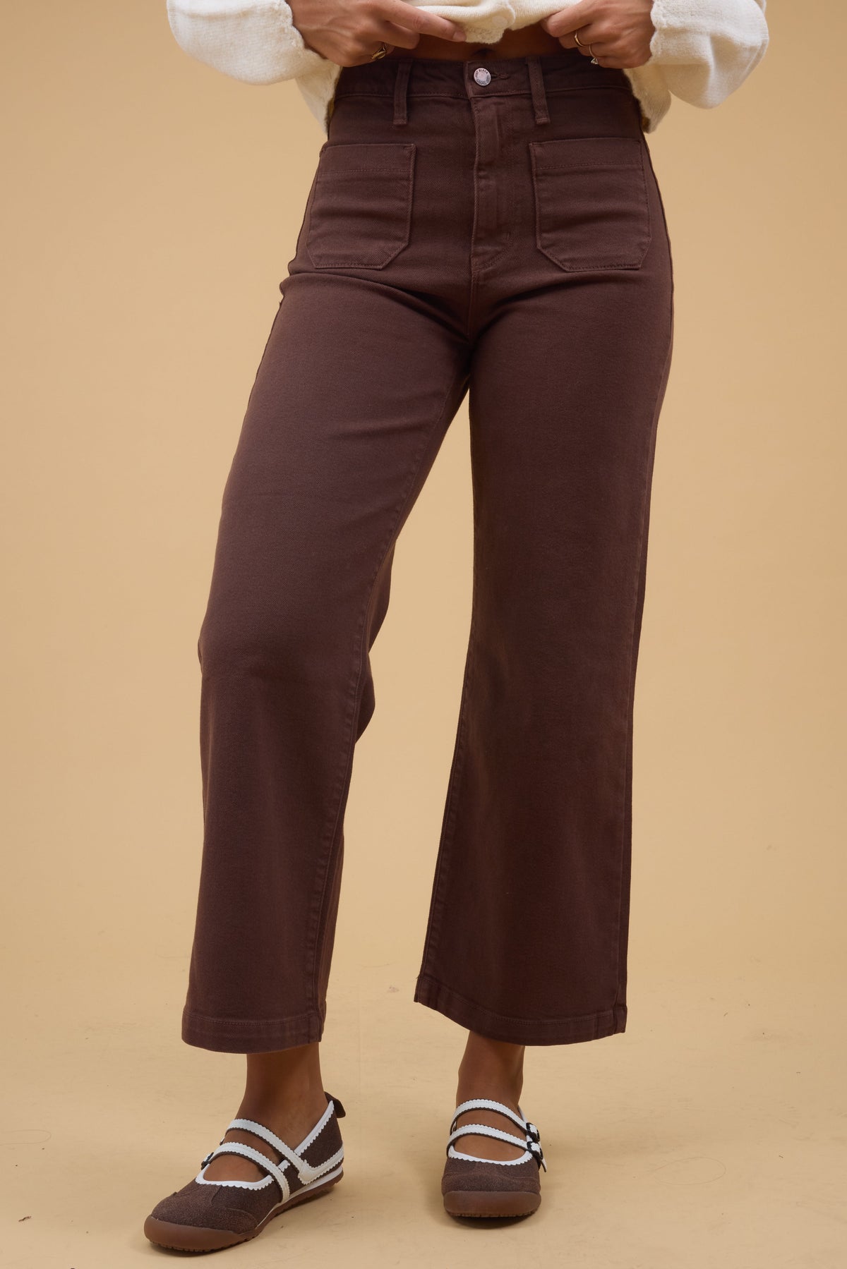 Young woman wearing a pair of brown wide leg jeans with front patch pockes