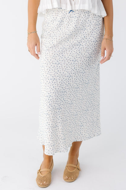 Young woman wearing a modest white with blue floral A-line midi skirt.