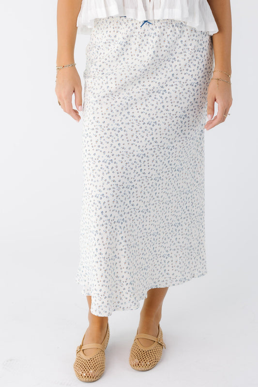 Young woman wearing a modest white with blue floral A-line midi skirt.