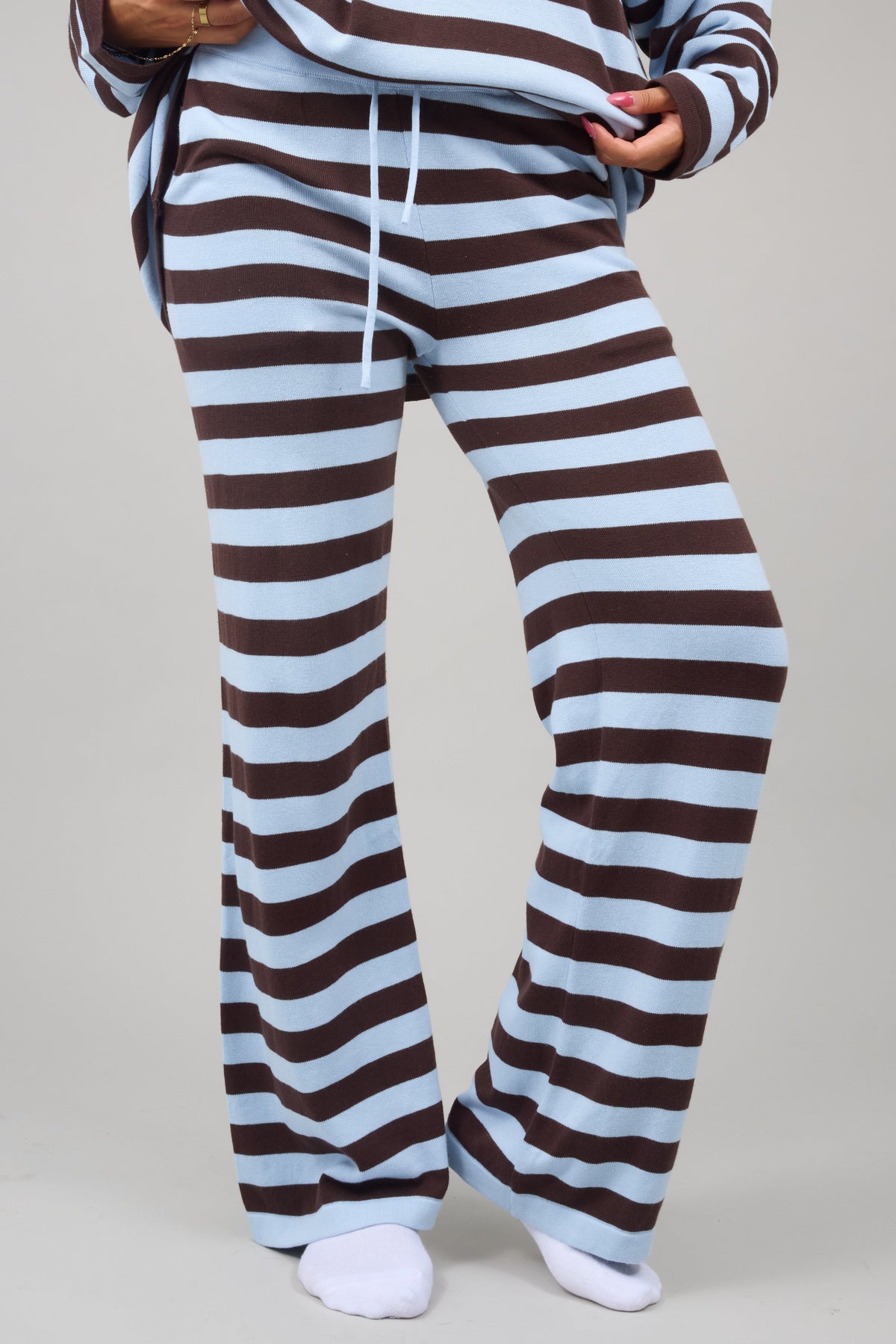 Young woman wearing modest light blue & brown stripe, wide leg lounge pants.
