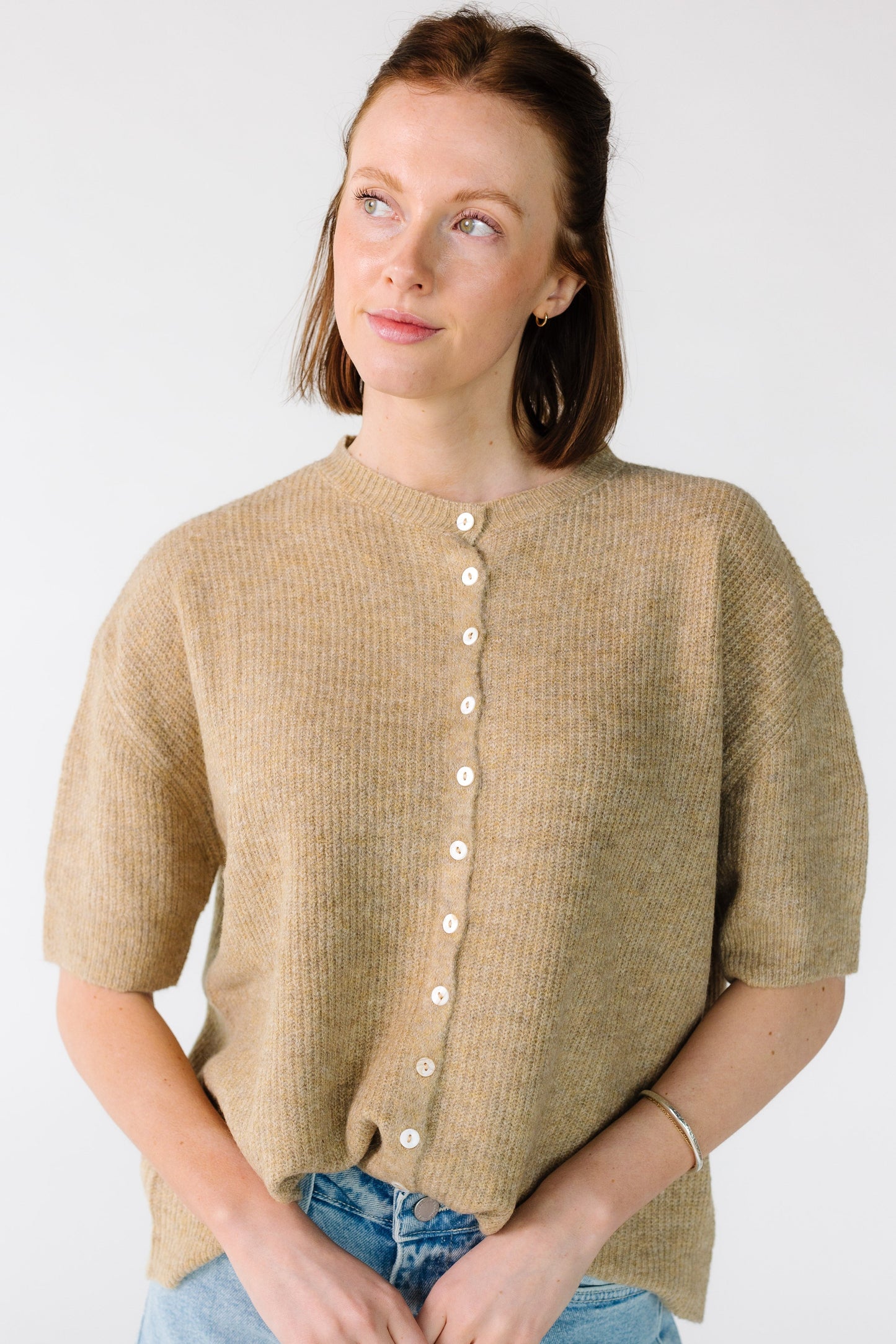 Young woman wearing a button down, rib knit cardigan with short sleeves.