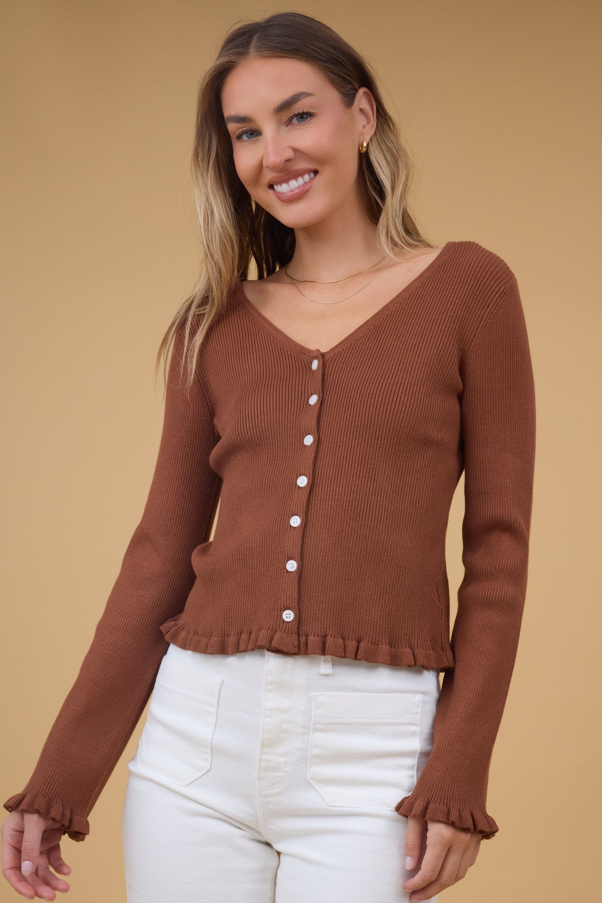 Young woman wearing a modest brown, rib knit, button down top with a wide V-necklineand ruffles and the hem and cuffs.