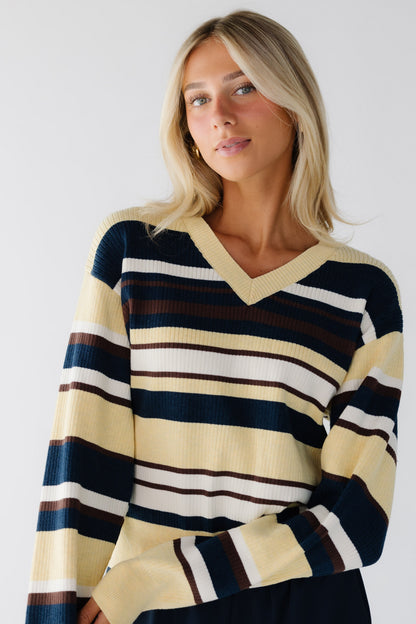 Young woman wearing a yellow and multi-color V-neck sweater with a V-neckline.