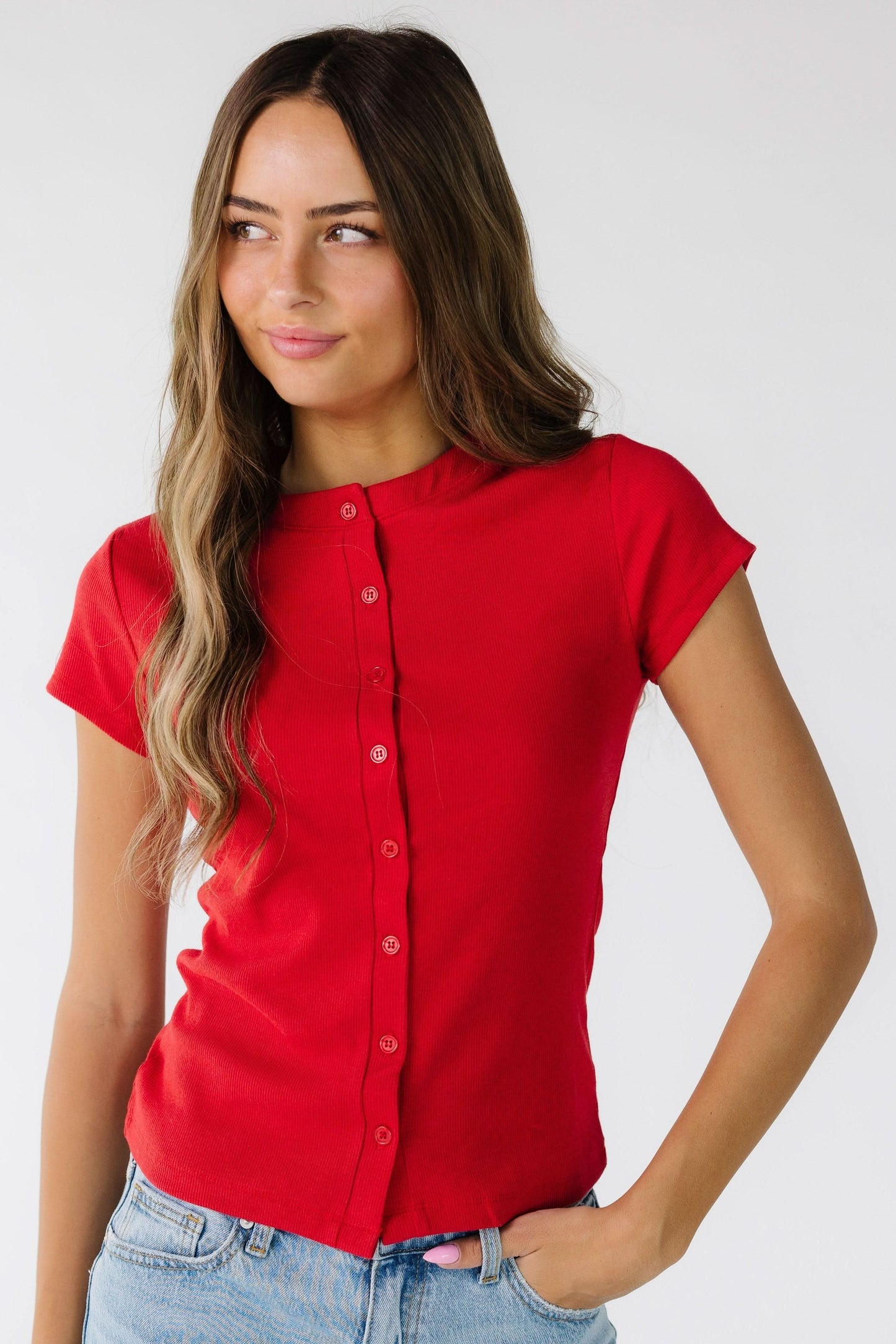 Woman wearing a modest red button down shirt with color matching buttons and short sleeves.