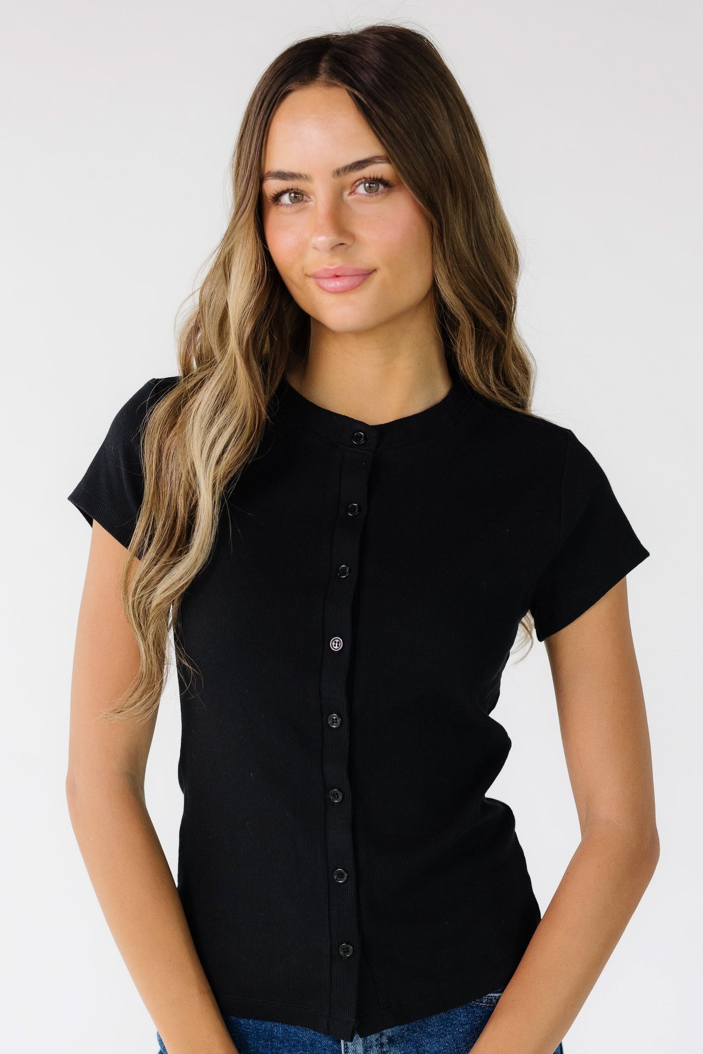 Woman wearing a modest black button down top with a round neckline and short sleeves.