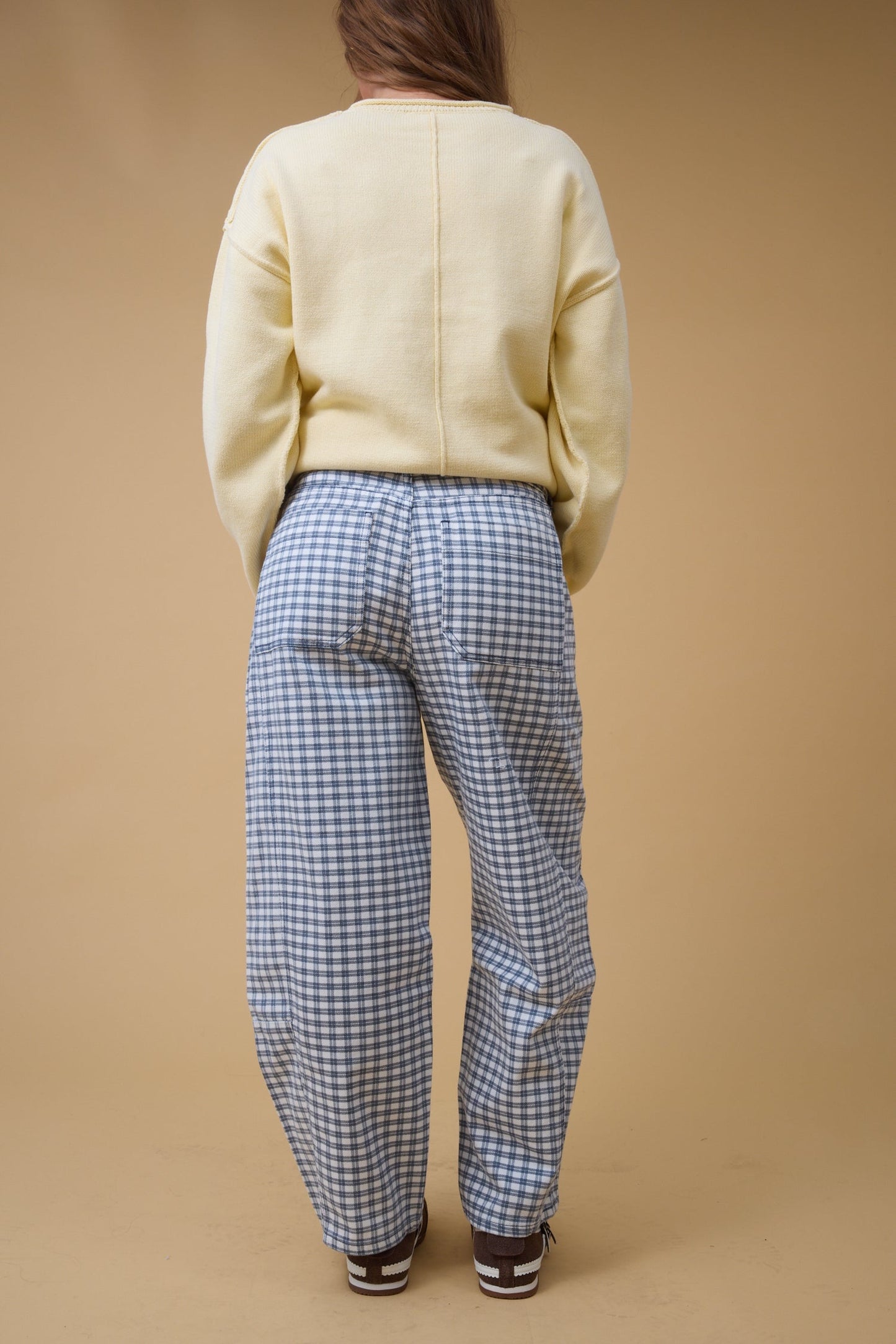 Back view of a young woman wearingwide leg navy plaid pants with large back pockets.