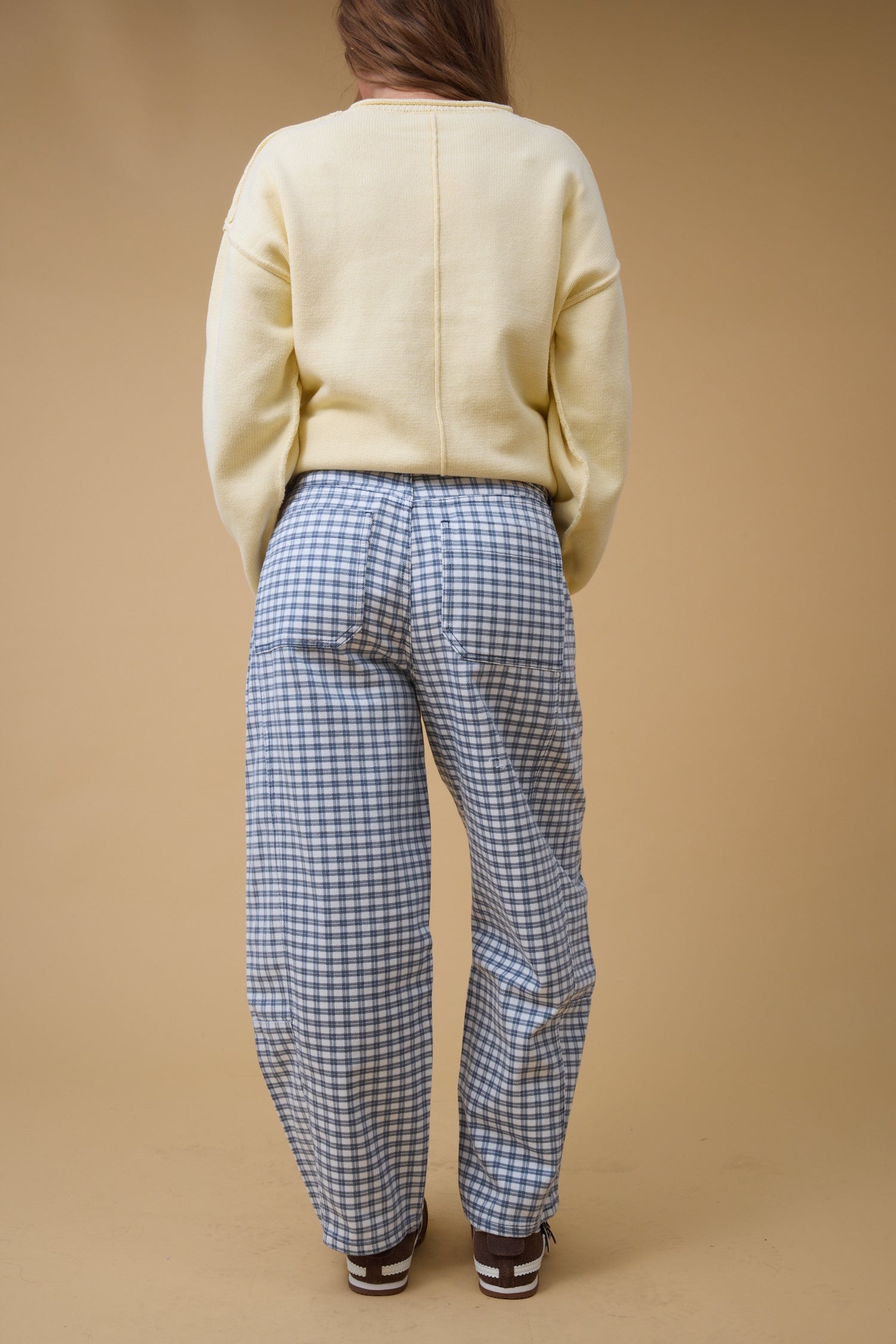Back view of a young woman wearingwide leg navy plaid pants with large back pockets.