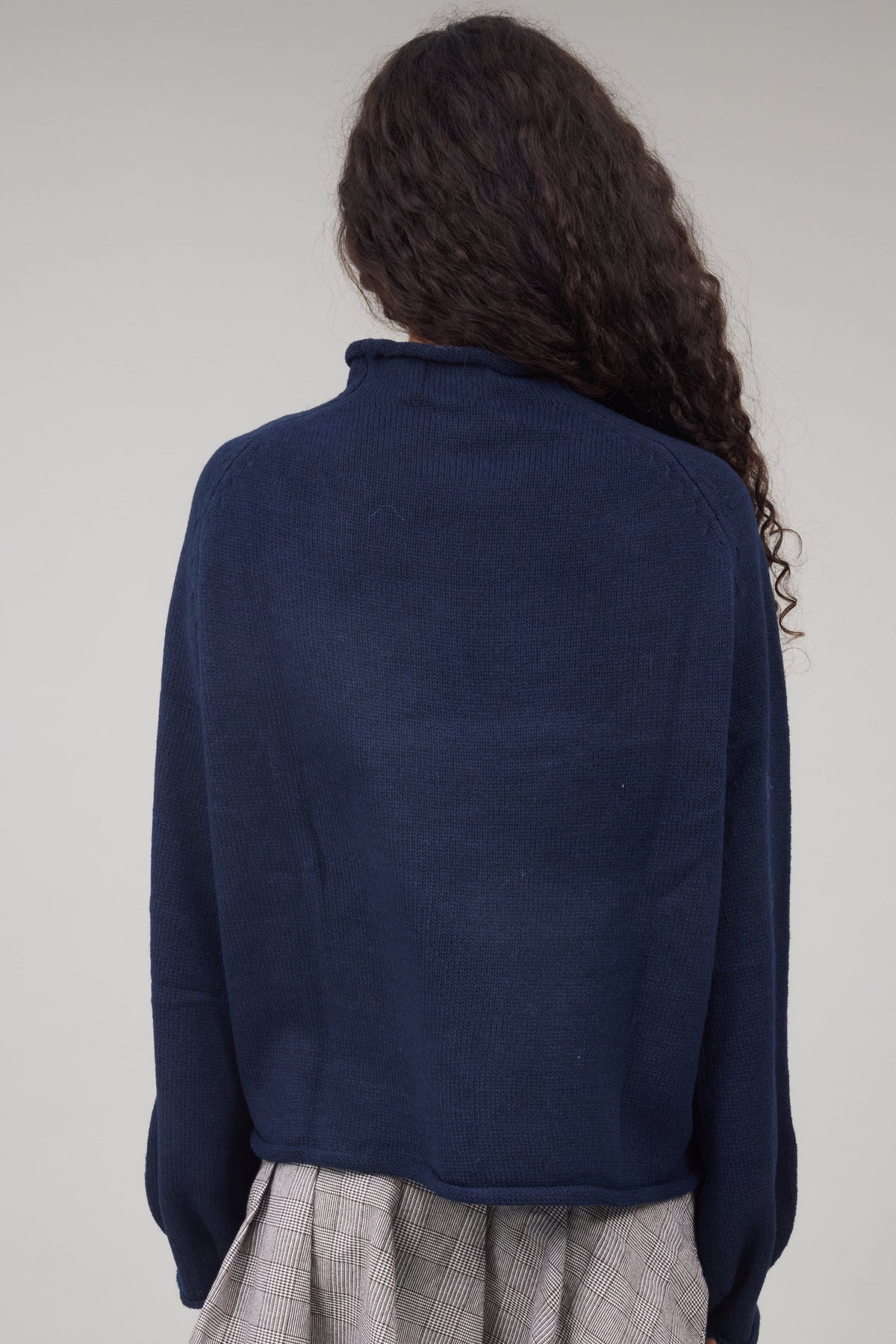 Back view of a woman wearing a navy oversized sweater with logn sleeves.